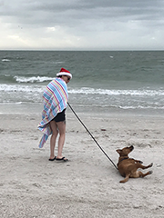 on the beach in a Santa hat and towel with dog
