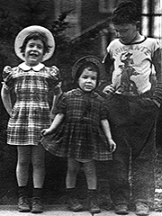 my sister and I in plaid dresses and hats with my brother wearing a vigilante shirt
