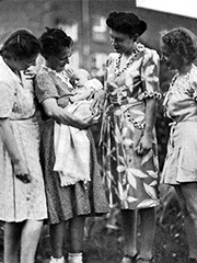 my brother as a baby being held by my paternal grandmother, with her daughters and my mother