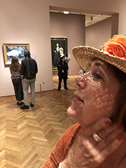 woman in art gallery with a hat casting shadows on her face
