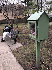 free library with man reading on bench nearby
