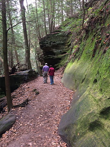 man and woman on path with mossy ridge and trees