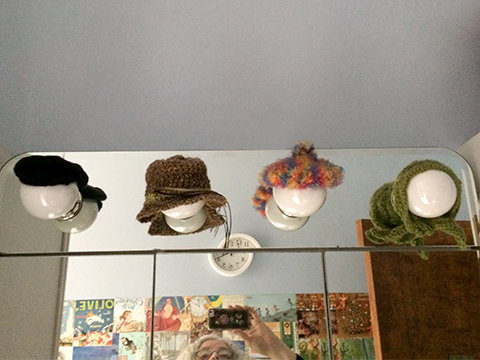 four lights over a bathroom mirror, each wearing a hat