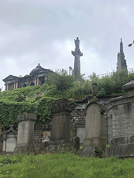 Tombstones, sculptures, and mausoleum on hill