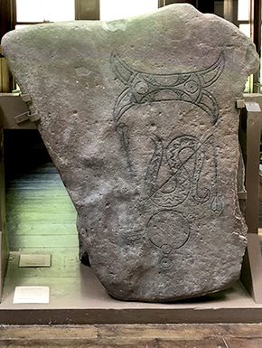 Stone carved with monseter? Owl? and snake
