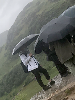 Slanted photos of people in rain with black umbrellas