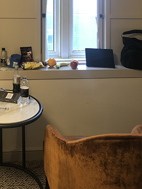 Chair and table pulled up to window, with fruit, book, and ipad