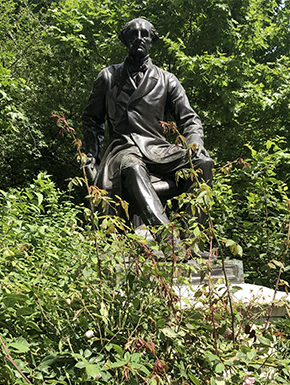 Sculpture of seated man with name hidden by greenery