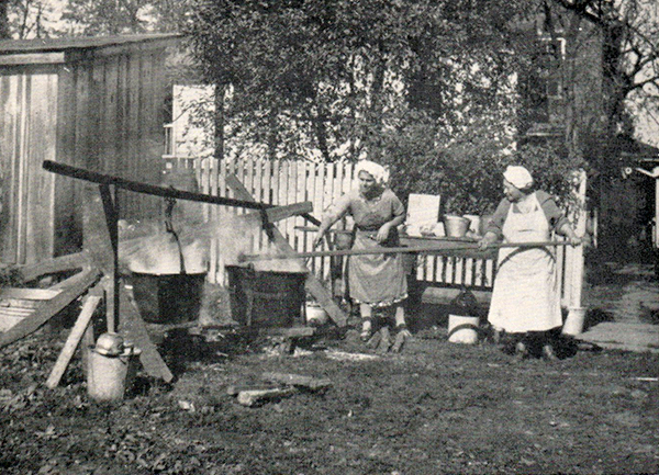 two women making apple butter in huge kettles, the old school way