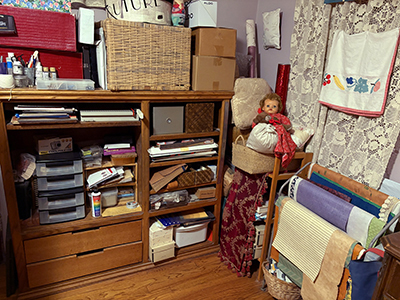 A cabinet full of supplies, and a quilt display but full of paper.