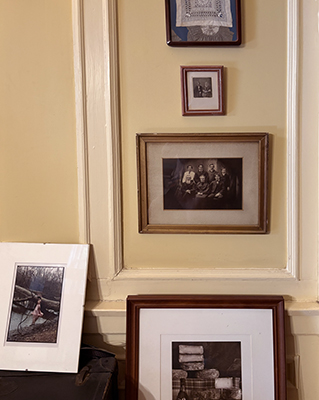 old photos on wall and on floor and an old suitcase